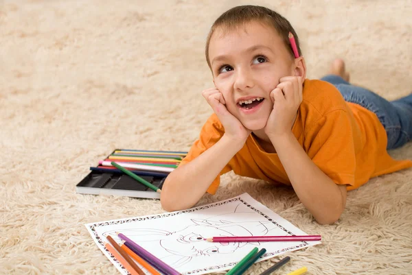 Kind mit Bleistift auf dem Teppich. — Stockfoto
