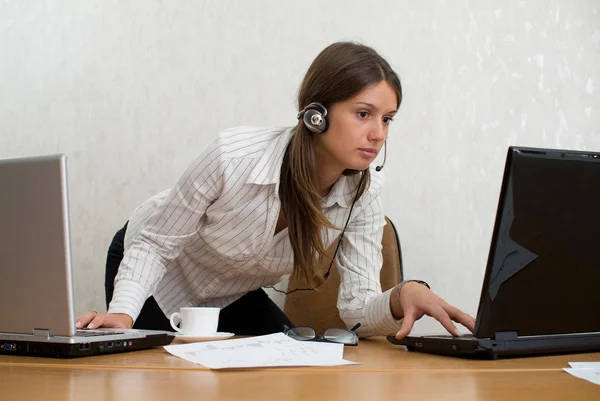 Молодая деловая женщина в офисе с двумя ноутбуками — стоковое фото