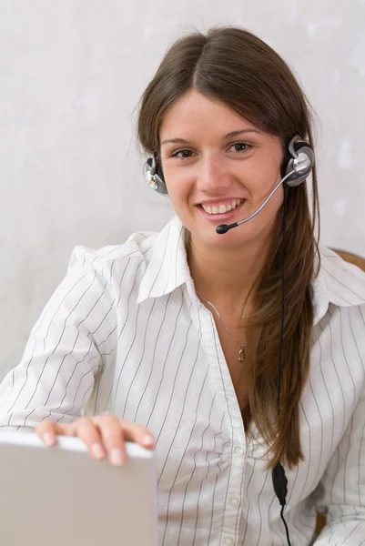 Beautiful girl in the office with a headset and a laptop — Stock Photo, Image