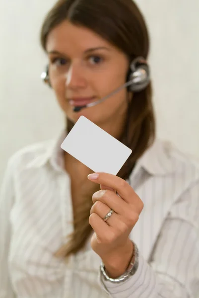 Jovem mulher de negócios bonita com um cartão de plástico e um fone de ouvido — Fotografia de Stock