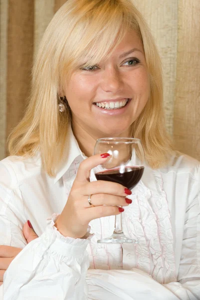Loira sorridente com um copo de vinho tinto — Fotografia de Stock