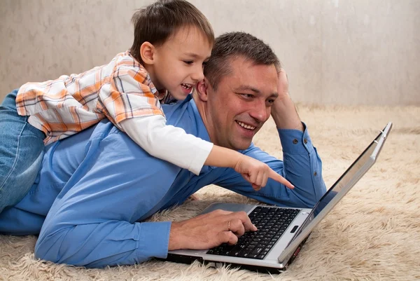 Ребенок с отцом наблюдает за ноутбуком — стоковое фото