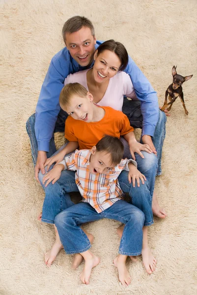 Семья сидит на белом ковре — стоковое фото