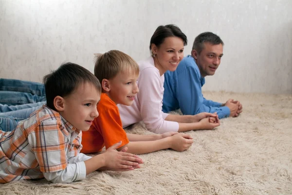 Family of four lying on the carpet — Stock Photo, Image