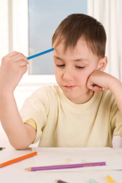 Pojke med en penna sitter och ritar — Stockfoto