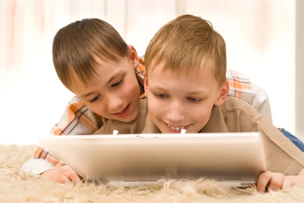 Twee broertjes liggen met laptop — Stockfoto