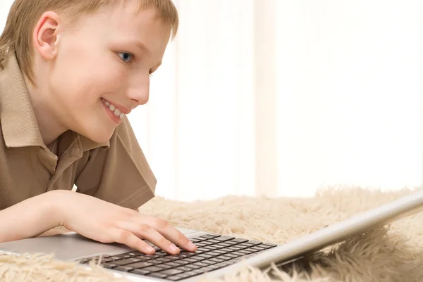 Menino feliz jogando em um laptop — Fotografia de Stock