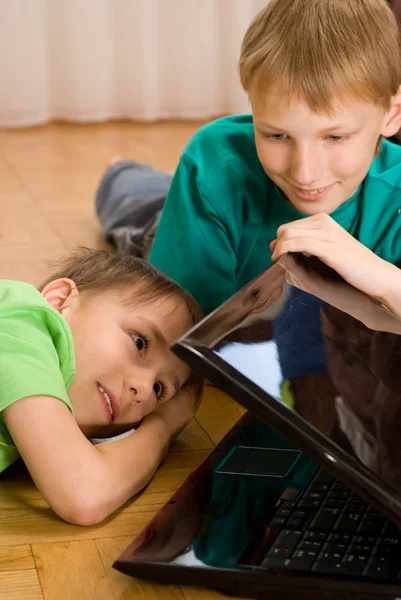 Brothers lie with laptop — Stock Photo, Image
