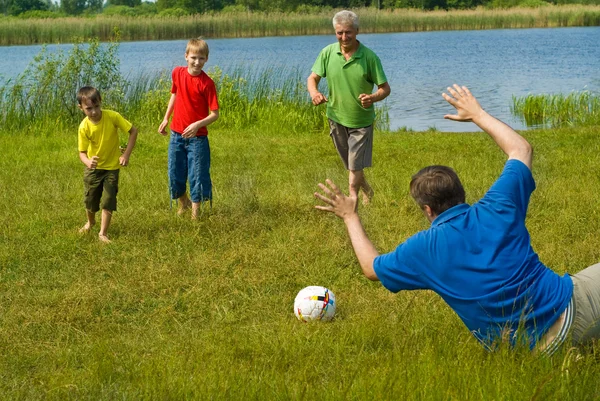 Семья играет в футбол на траве — стоковое фото