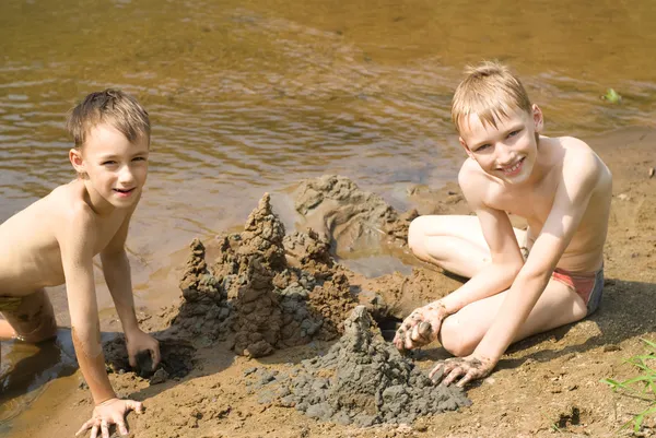 Zwei Kinder bauen eine Sandburg — Stockfoto