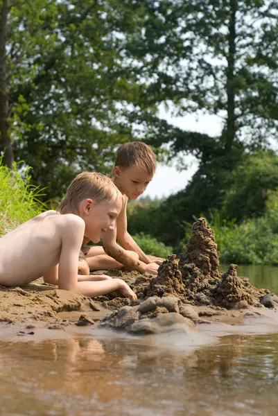Двое детей строят замок из песка — стоковое фото