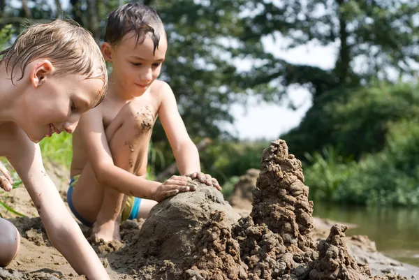 Two children build a sand castle — Stock Photo, Image