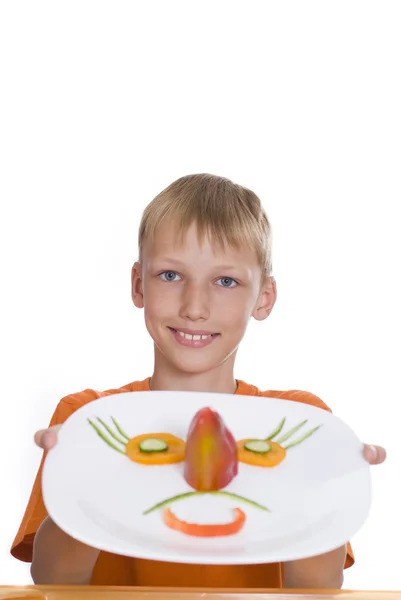 Beau garçon tenant une assiette avec des légumes — Photo