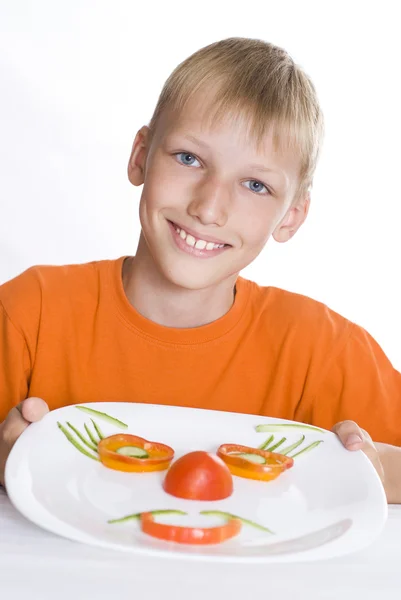 Beau garçon tenant une assiette avec des légumes — Photo