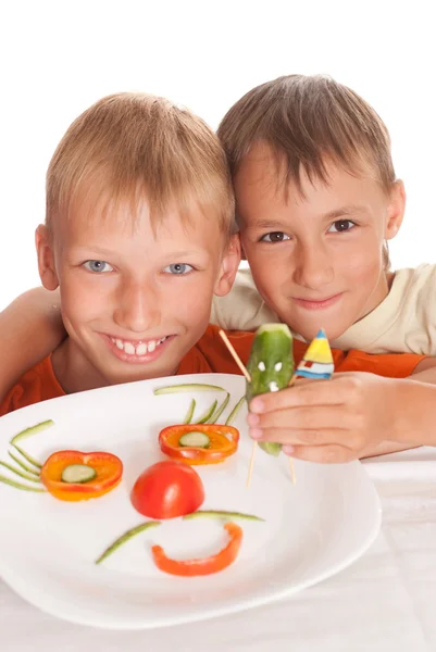 Vackra pojke håller en tallrik med grönsaker — Stockfoto