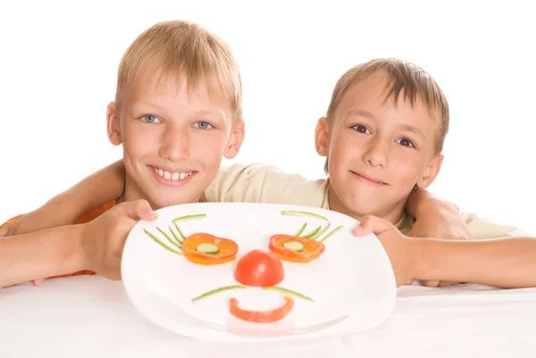 Красивый мальчик держит тарелку с овощами — стоковое фото