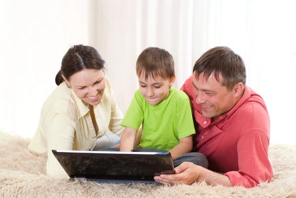 Glücklicher Junge mit Laptop bei den Eltern — Stockfoto