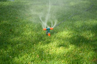 Sprinkler Spraying Water On Grass clipart