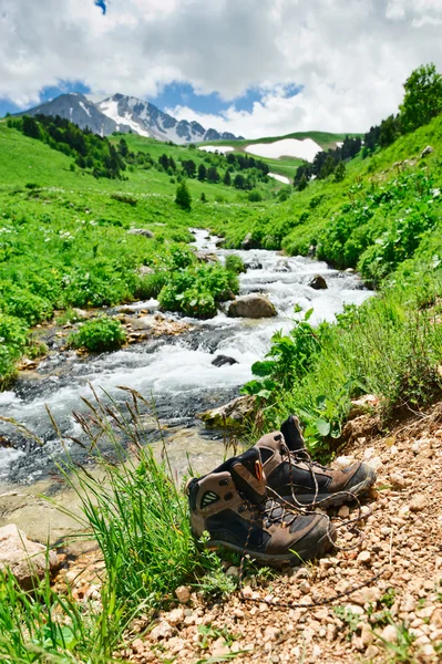 Scarponi da passeggio davanti a un torrente di montagna — Foto Stock