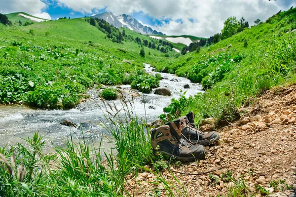 Botas de paseo frente a un arroyo de montaña — Foto de Stock