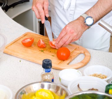 Chef cutting the tomato on a wooden board clipart