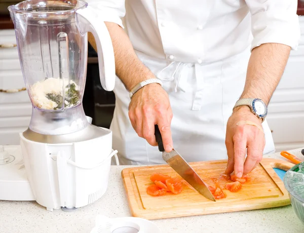 Koch schneidet die Tomaten auf einem Holzbrett — Stockfoto