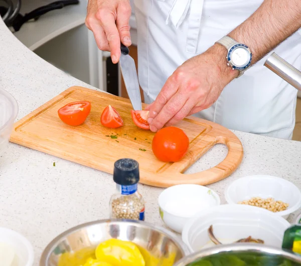 Chef cortando o tomate em uma placa de madeira — Fotografia de Stock