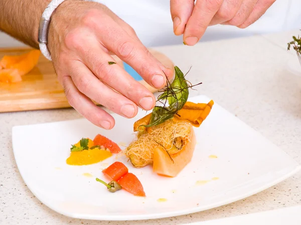 Шеф-повар украшает тарелку едой — стоковое фото