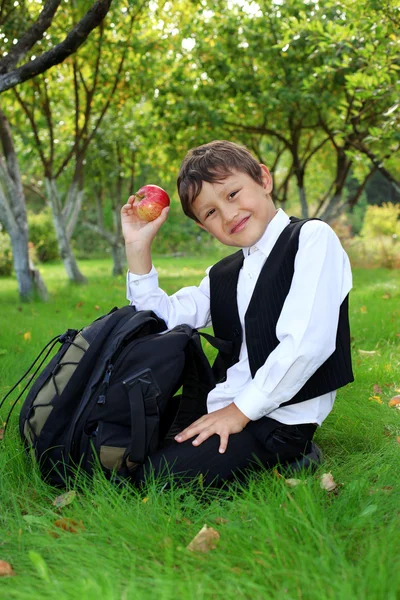 Школьник с рюкзаком и яблоком на открытом воздухе — стоковое фото