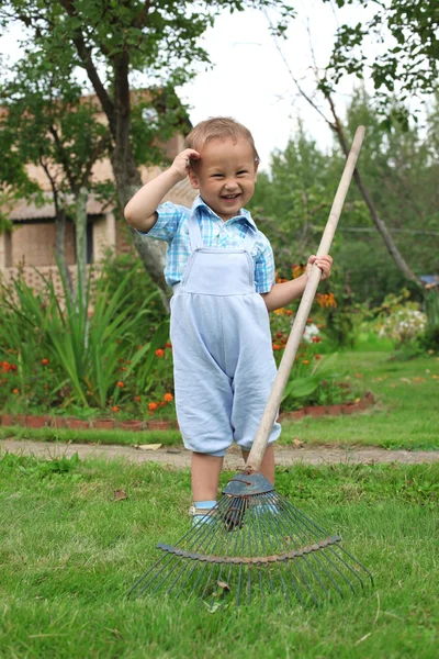 Petit garçon ratissant dans le jardin — Photo