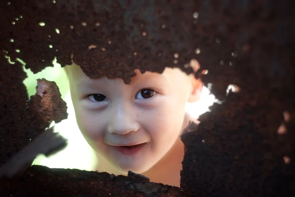 Funny baby gömmer sig bakom rostiga gamla stål — Stockfoto