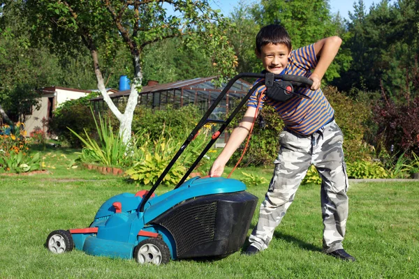 Мальчик-садовник стрижет газон — стоковое фото