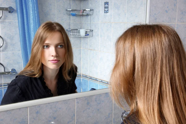 Νεαρή γυναίκα στο λουτρό μπροστά από έναν καθρέφτη — Φωτογραφία Αρχείου