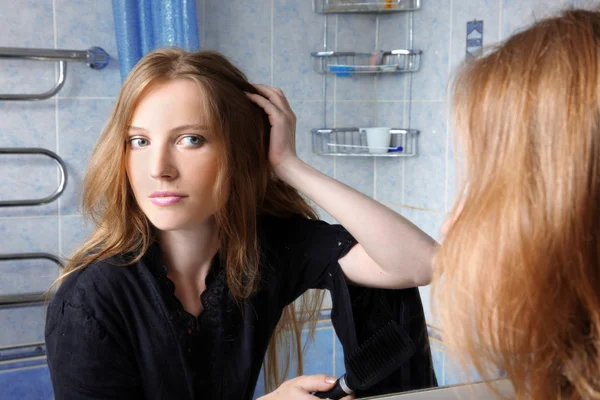 Mujer joven en el baño delante de un espejo corrigiendo pelos —  Fotos de Stock