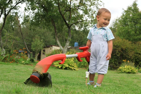Giovane bambino con trimmer in giardino — Foto Stock