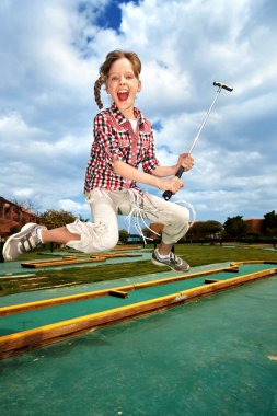 Little girl playing golf in park. clipart