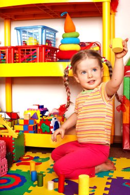 Child with puzzle and wood block in play room. clipart