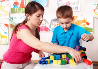 Child with construction in play room. clipart