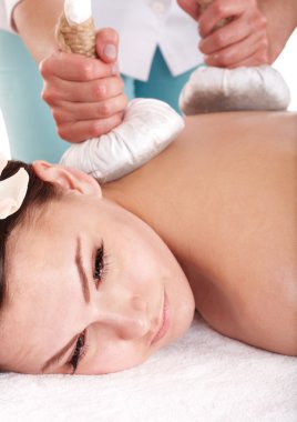 Girl having Thai herb compress massage in beauty spa. clipart