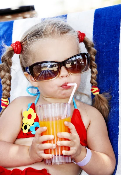 Child in glasses and red bikini drink juice. — Stock Photo, Image