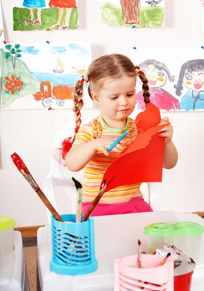 Ребёнок с ножницами режет бумагу в игровой комнате . — стоковое фото