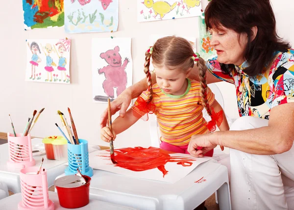 Niño con el maestro dibuja pinturas en la sala de juegos . — Foto de Stock
