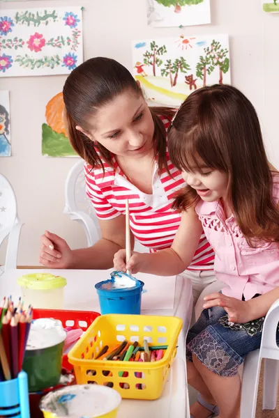 Child with teacher draw paints in play room. — Stock Photo, Image
