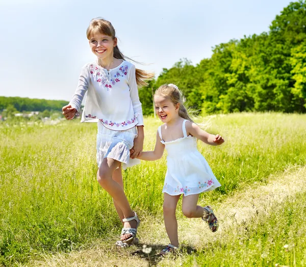 Τα παιδιά που τρέχουν πέρα από το πράσινο γρασίδι εξωτερική. — Φωτογραφία Αρχείου