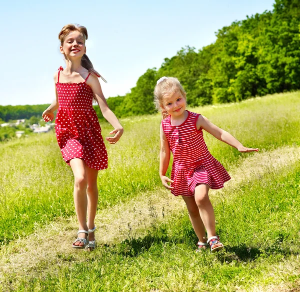 Barn löper över grönt gräs utomhus. — Stockfoto