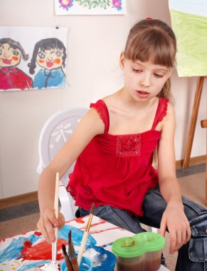 Child with picture and brush in playroom. clipart