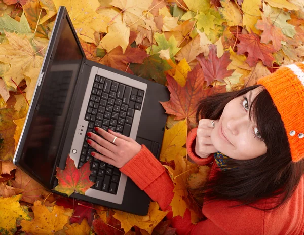 Girl in autumn orange foliage with laptop. — Stock Photo, Image