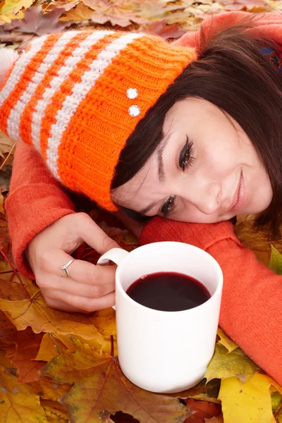 Meisje in herfst oranje bladeren met een kopje koffie. — Stockfoto