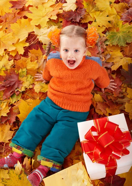 Child in autumn orange leaves and gift box. — Stock Photo, Image
