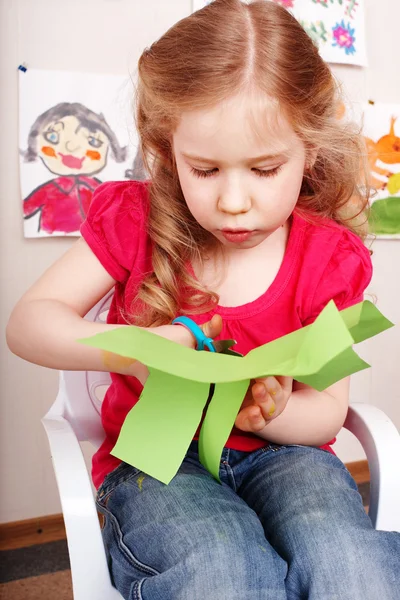 Kind met scharen snijdt papier thuis. — Stockfoto